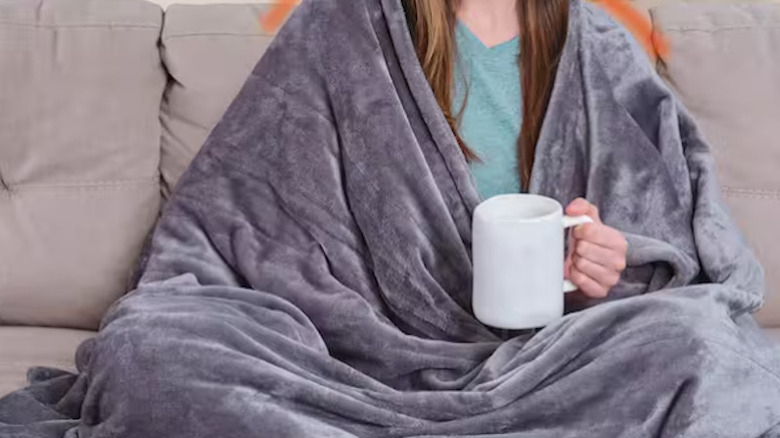The Handy Heater throw blanket wrapped around a person on a couch