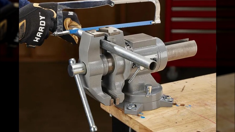 sawing a pipe while using vise