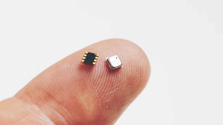 Two units of the Bosch BME688 Digital Nose ai-enabled sensor balanced on a man's fingertip, one upright and one inverted.
