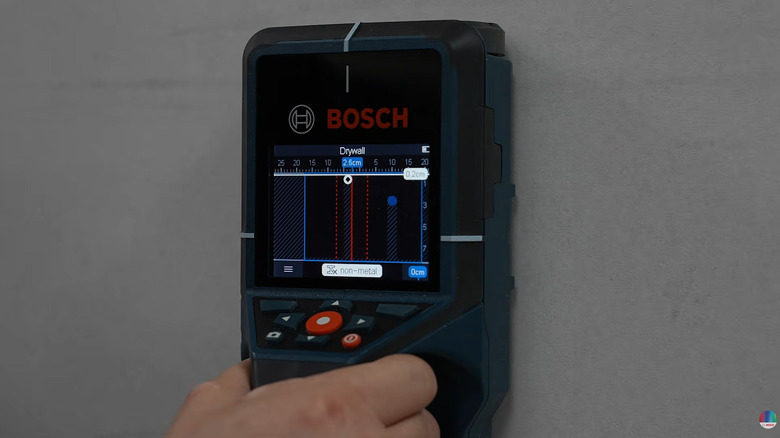 A man holding the Bosch D-tect 200C wall scanner to scan a section of wall in the device's non-metal detection mode.