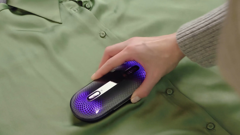 The Bosch FreshUp plasma-powered odor remover in action on a green shirt, with the purple LED indicators glowing.