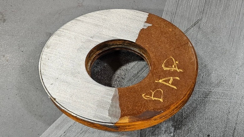 Metal disc with one side showing clean metal and the other showing rust