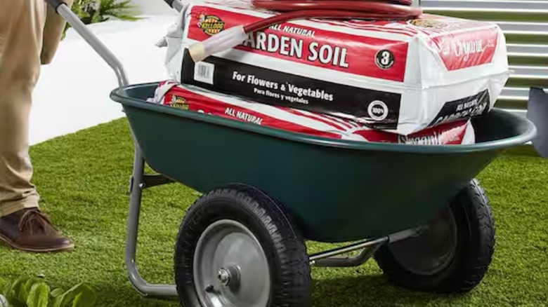 A worker moving bags of soil with wheelbarrow cart