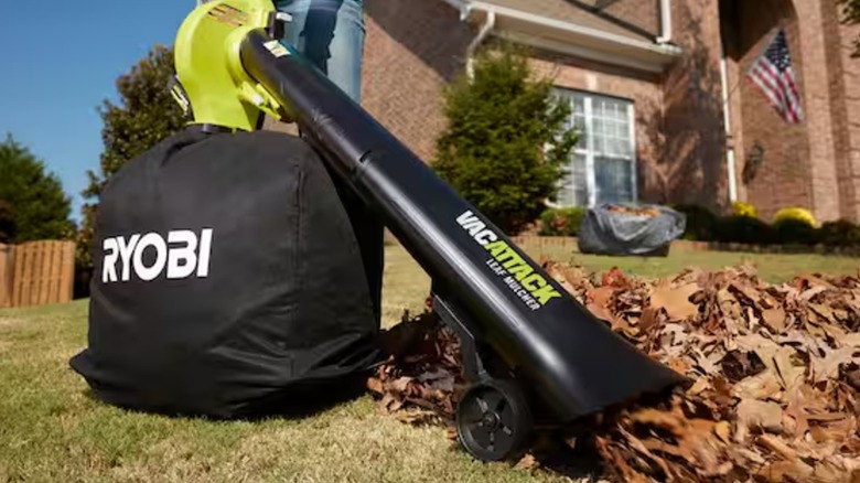 A Ryobi vacuum/mulcher sucking up leaves on a residential lawn