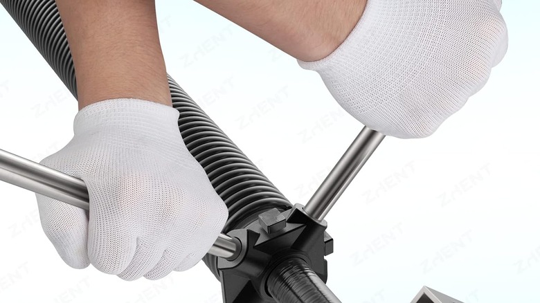 A spring being loaded onto a garage door.