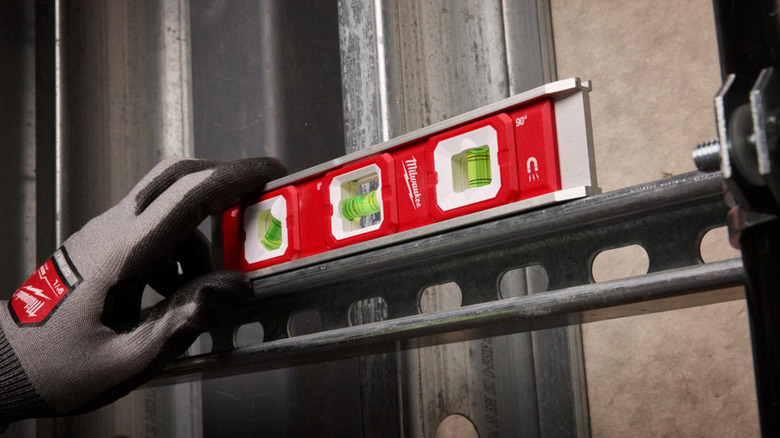 Using a Milwaukee torpedo level to check material alignment.