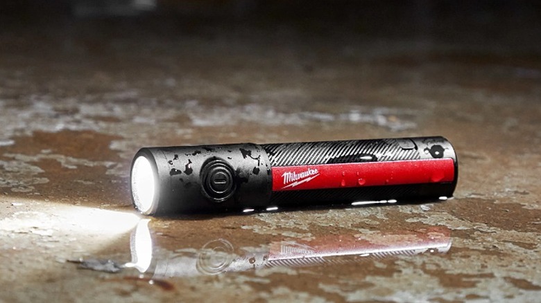 Milwaukee mini flashlight placed on a marble surface.