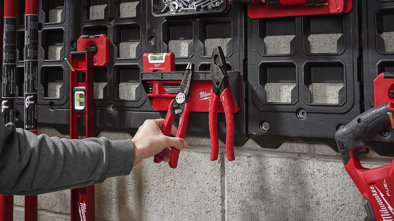 Several Milwaukee hand and power tools hung on a magnetic wall board.