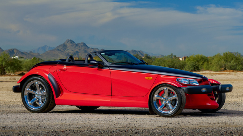 Red and black plymouth prowler parked on gravel
