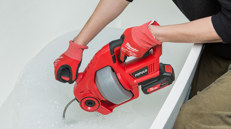 person using Populo drain auger in bath tub