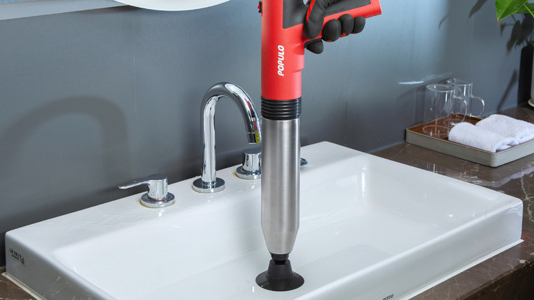 person using popular plunger on sink