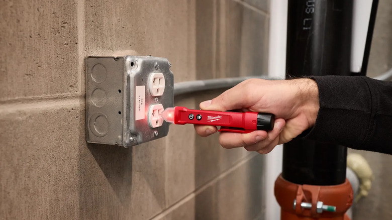 A person putting a tool in an outlet.