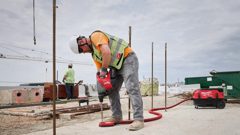 A rotary hammer being used by someone in safety equipment.