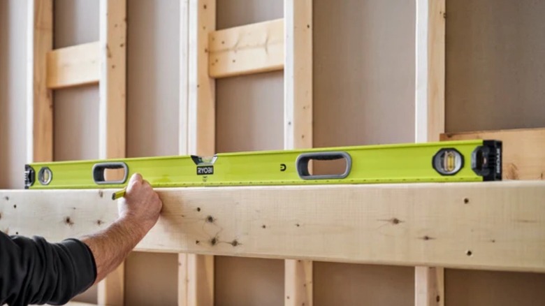 Person using Ryobi box level on stub while building a house.