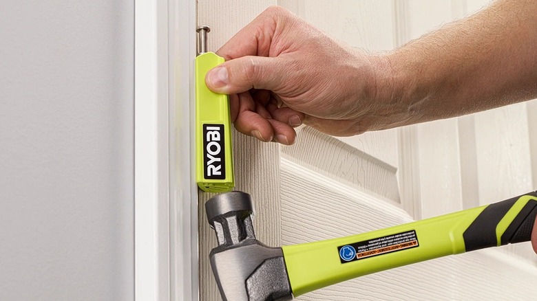 Person using a hammer with a Ryobi door hinge pin remover.