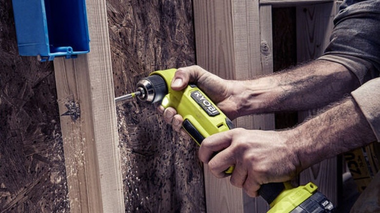 Person drilling through stub using Ryobi right angle drill.