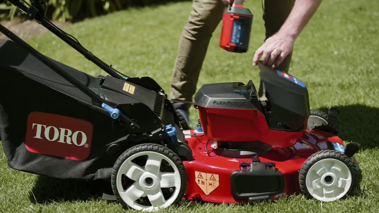A person putting a battery in a lawn mower