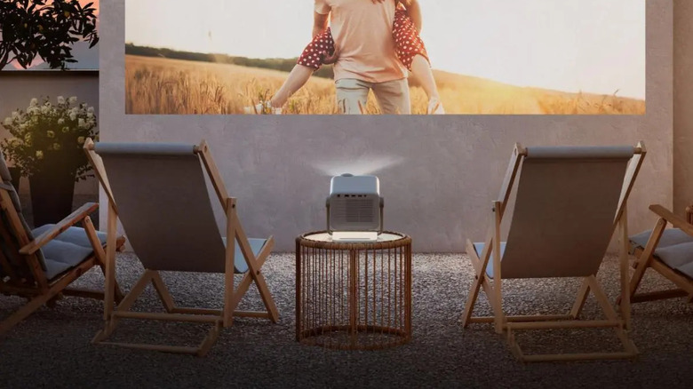 The Hisense M2 Pro projecting onto a wall outside, with a few lawn chairs around it