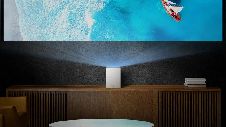 The LG CineBeam S placed on a TV unit, projecting onto a grayish-black wall