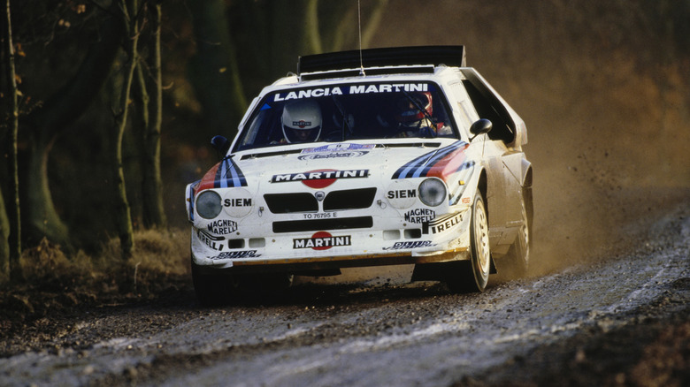 Front 3/4 shot of a Lancia Delta S4 kicking up dirt on a rally stage.