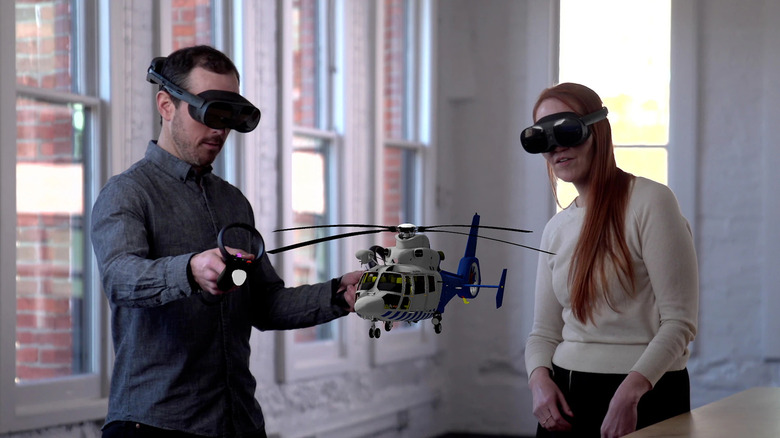 Two people wearing the HTC Vive XR Elite with a virtual helicopter in front of them