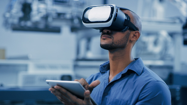 A person using a VR headset while holding a tablet