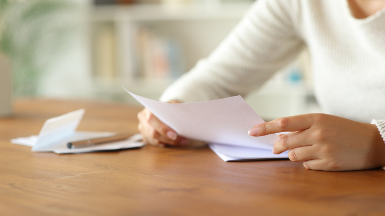 Person reading a letter at a table.