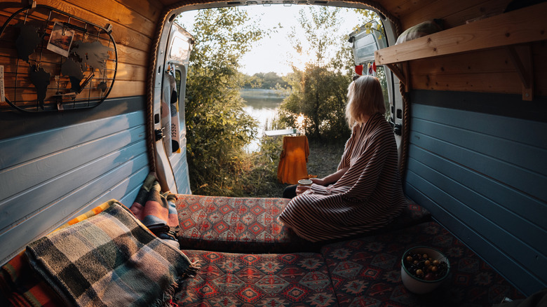 Person sitting in a van and looking out on a lake.