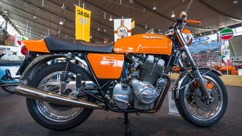 1973 Laverda 1000 3C in vibrant orange with full fairing, parked at a classic vehicle gathering.