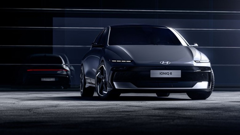 A gray Hyundai Ioniq 6 (non-N-line model shown) standing in a dark studio environment, with its reflection shown t in the back.