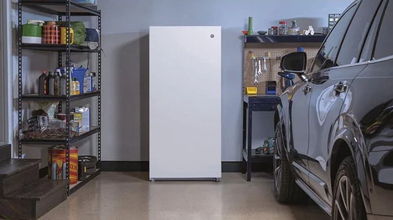 White upright freezer placed in a garage.
