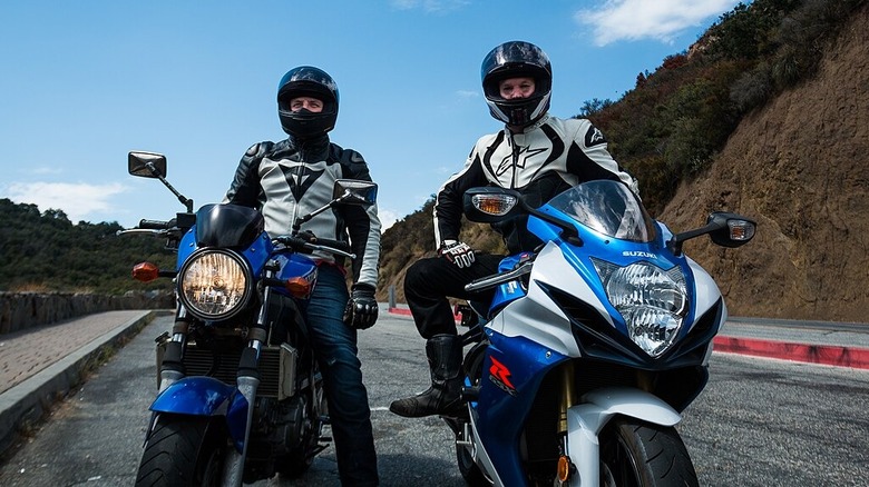 Two motorcyclists wearing helmets with visors up