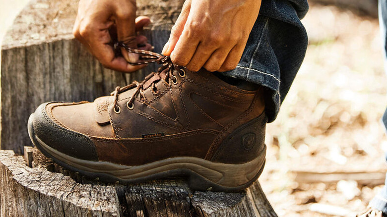 A person lacing up their Ariat Men's Terrain Hiking Boots