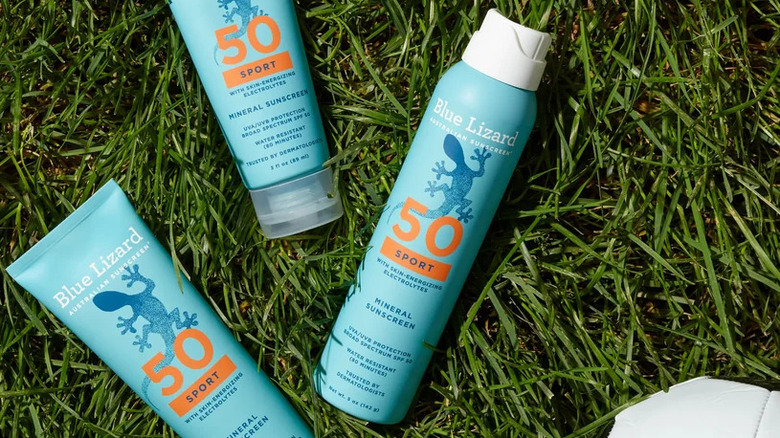 The Blue Lizard Sport SPF 50 Spray placed on grass next to some Blue Lizard sunscreens