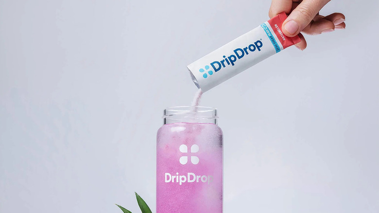 The DripDrop Hydration Zero Sugar Plus satchet being poured into a bottle of water