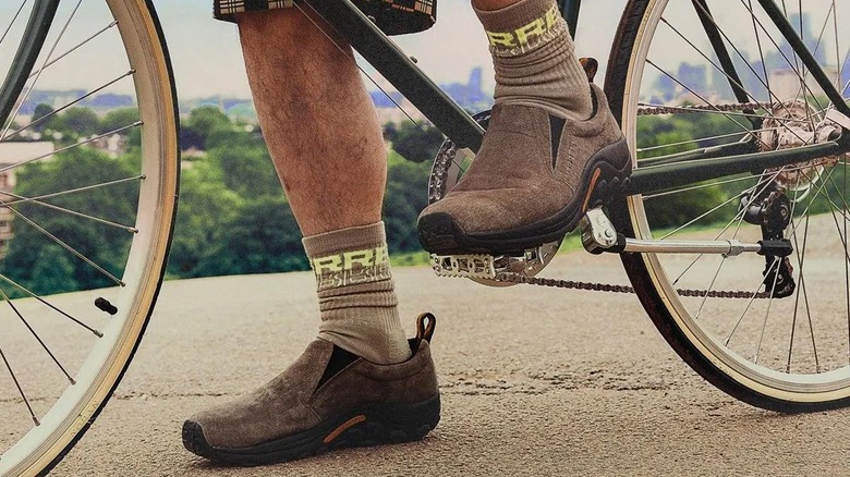A person riding a bicycle while wearing the Merrell Men's Jungle Moc Water-Resistant Boots