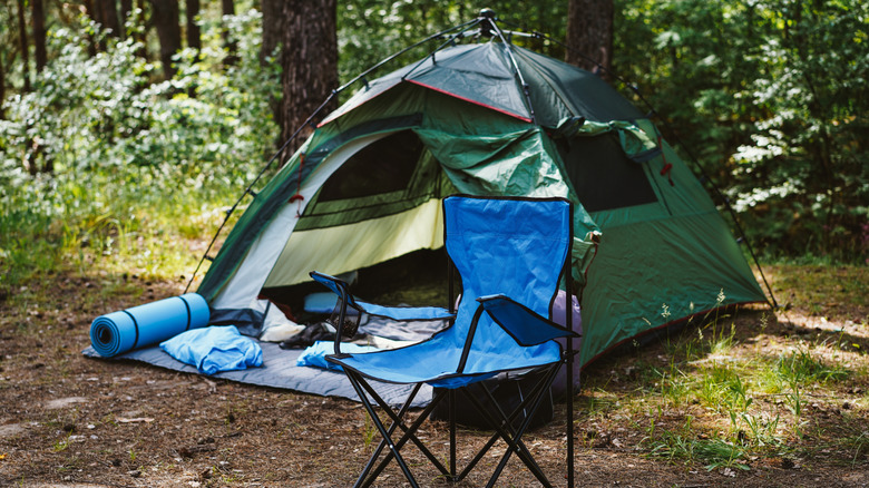 A tent and chair out in the woods
