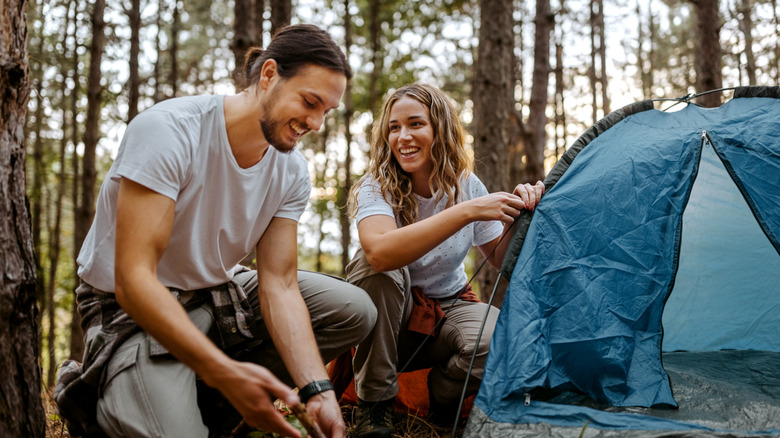 Two people pitching a tent outdoors