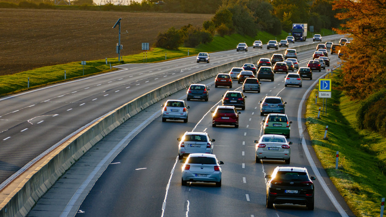 Many cars traveling on a highway, viewed from behind and above.