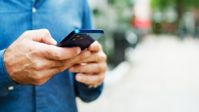 A person, their face off-camera, holding a smartphone.