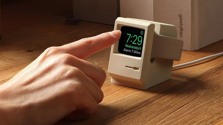 A person pointing at the face of a smartwatch that's showing the time, placed on the elago W3 Stand