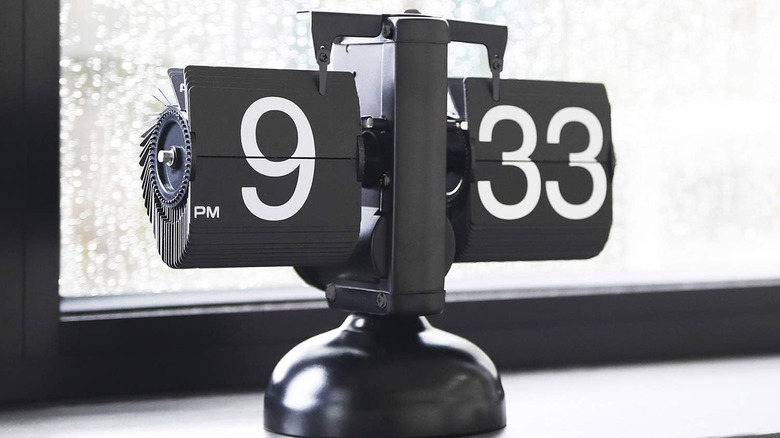 A black Mooas Flip Desk Clock placed in front of a window with rain on it