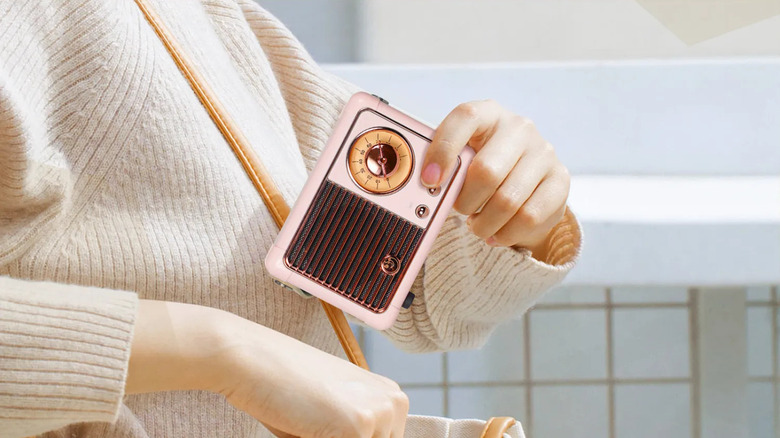 A person holding a Prunus J-999 Retro Bluetooth Speaker in their hand, wearing a white sweater