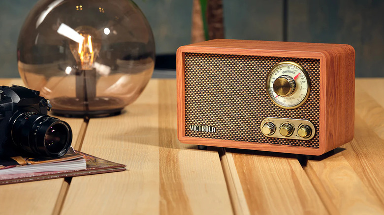 The Victrola Willow Retro Wood Bluetooth Radio placed on a wooden surface, next to a camera