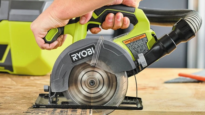 Using a Ryobi circular saw to cut through wood.