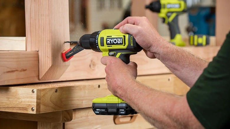 Using drill to drill holes in a wooden structure.
