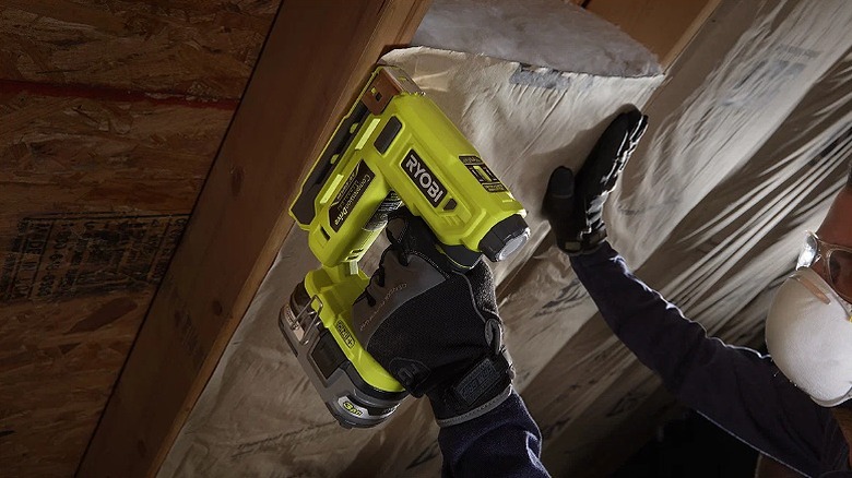 Using a crown stapler to secure fabric to a roof.