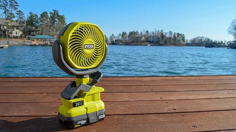 Clamp fan placed on a wooden surface near water.