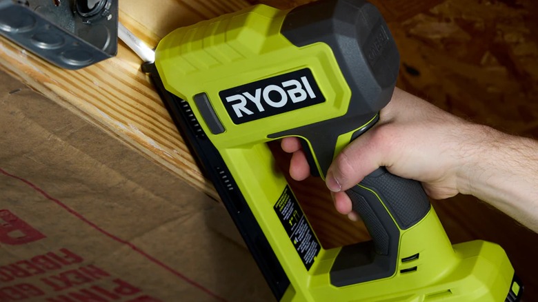 Worker stapling cables to wooden joist with Ryobi stapler