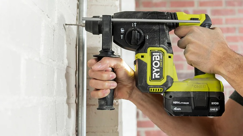 A worker drilling into concrete wall with Ryobi SDS hammer